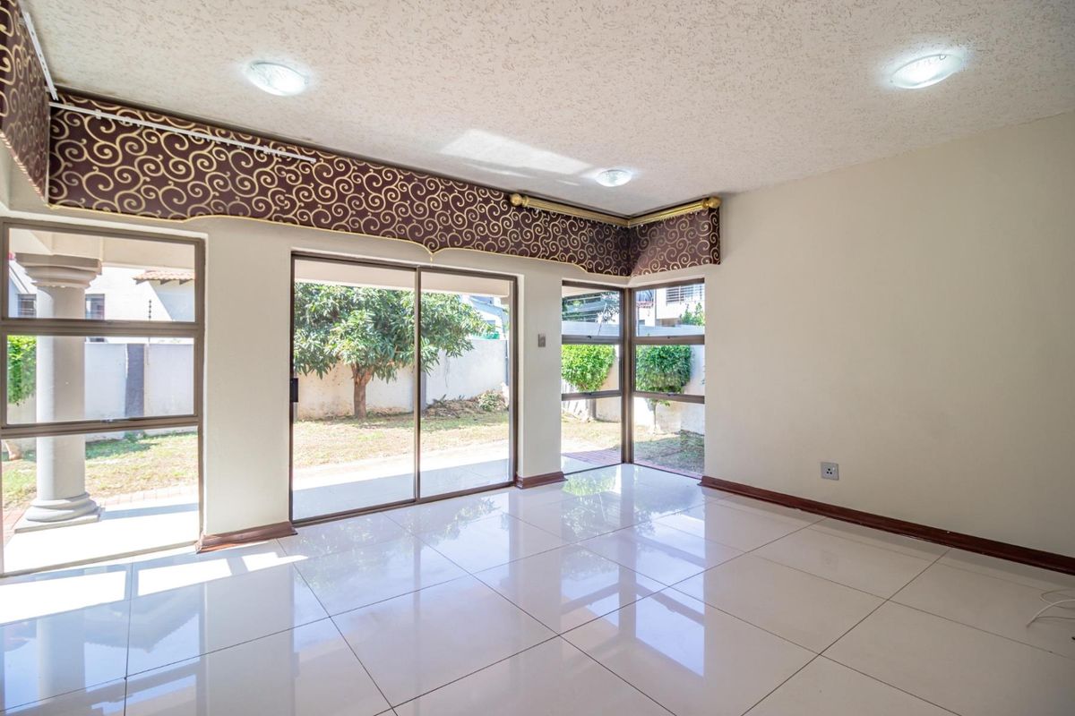 Bright living area featuring large sliding glass doors, polished floor tiles, and recessed lighting, offering direct access to the rear garden.