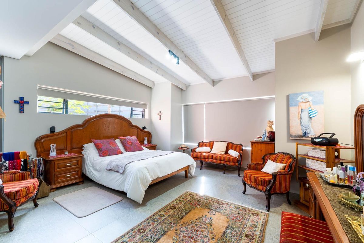 Spacious bedroom featuring high vaulted ceilings with exposed timber beams, large windows, and neutral wall finishes.