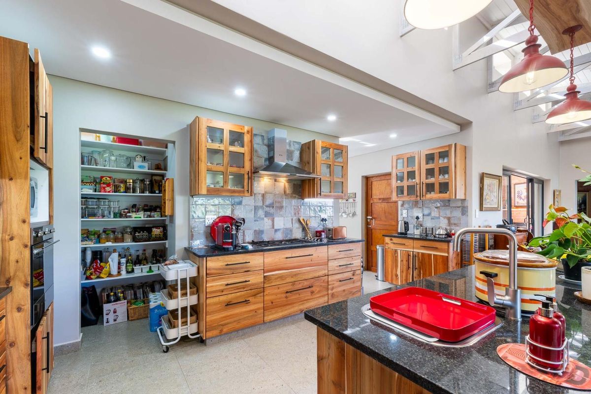 Spacious kitchen featuring natural wood cabinetry, granite countertops, a built-in gas hob with extractor fan, and a convenient walk-in pantry.