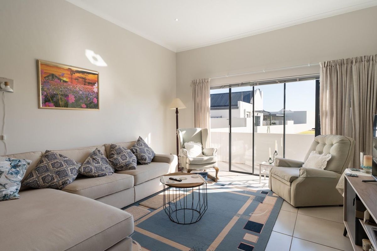 A bright and airy living room featuring large sliding glass doors that open onto a private balcony, providing ample natural light.