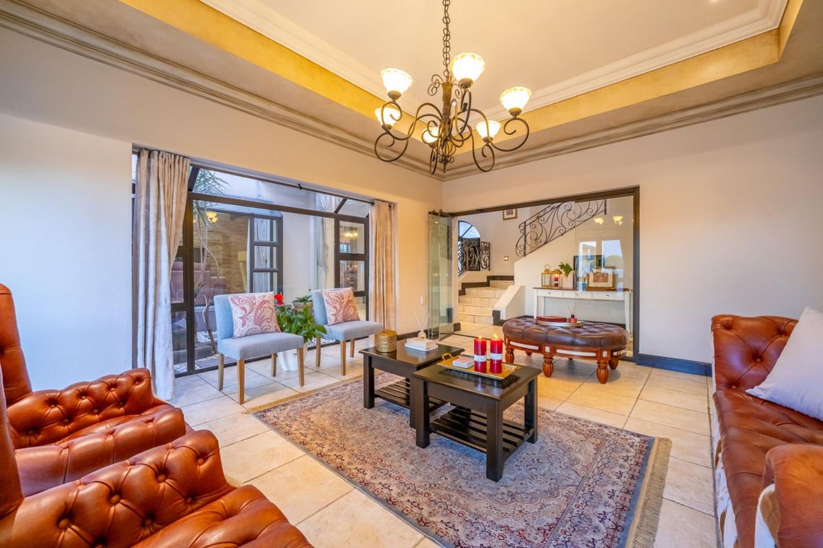 Spacious living area featuring tiled flooring, a decorative tray ceiling with chandelier, and large glass sliding doors leading to an outdoor space.
