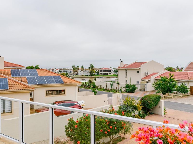 Elevated view from a balcony overlooking a residential neighbourhood with tiled roofs, solar panels, and landscaped gardens.