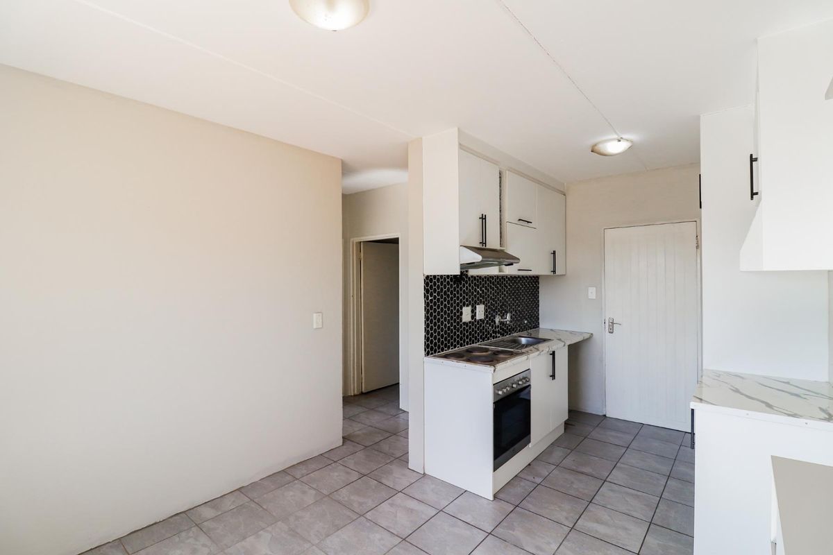 Compact kitchen featuring white cabinetry, mosaic tile backsplash, built-in oven and hob, and tiled flooring in a clean, functional layout.