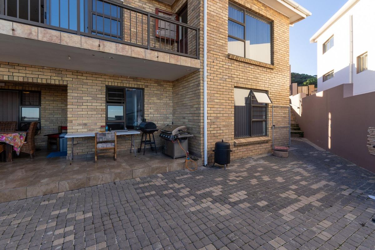 Rear exterior view of the townhouse featuring a paved courtyard, covered patio area, and brick facade with balcony access.