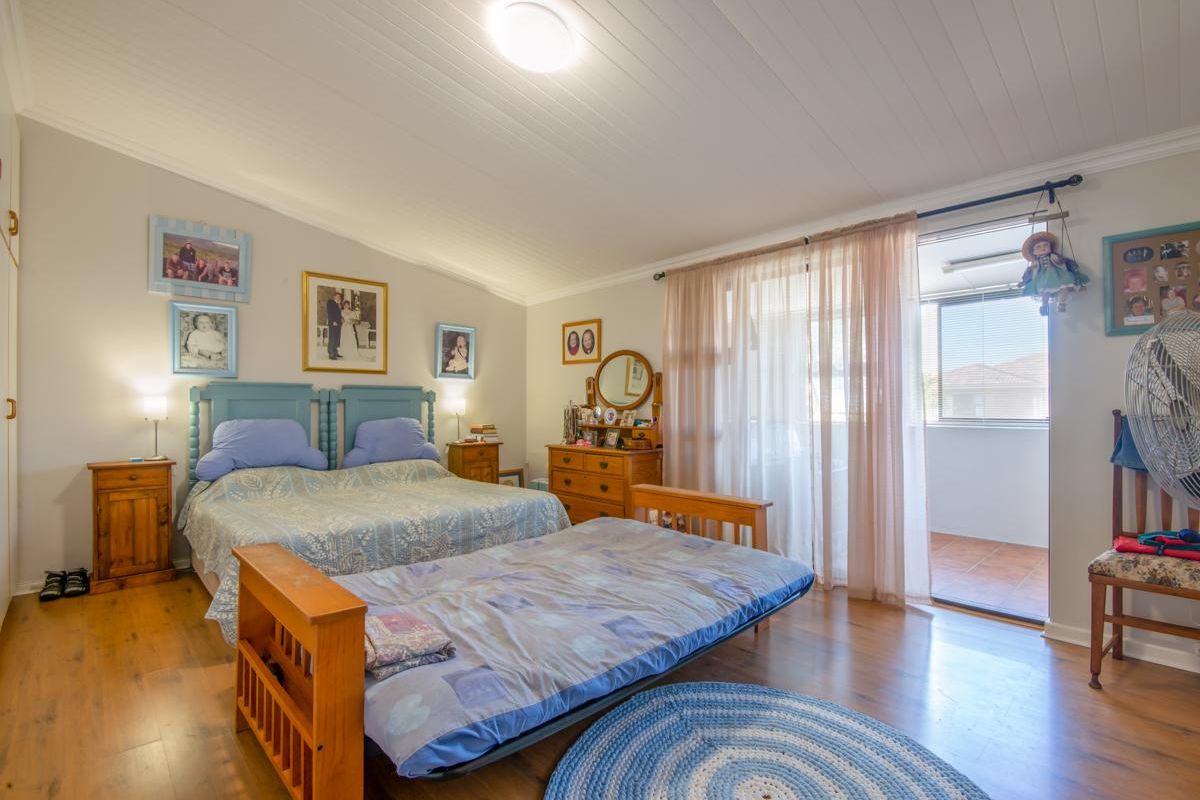 A spacious bedroom featuring wood-look flooring, a tongue-and-groove ceiling, and direct access to an adjoining balcony through a sliding glass door.