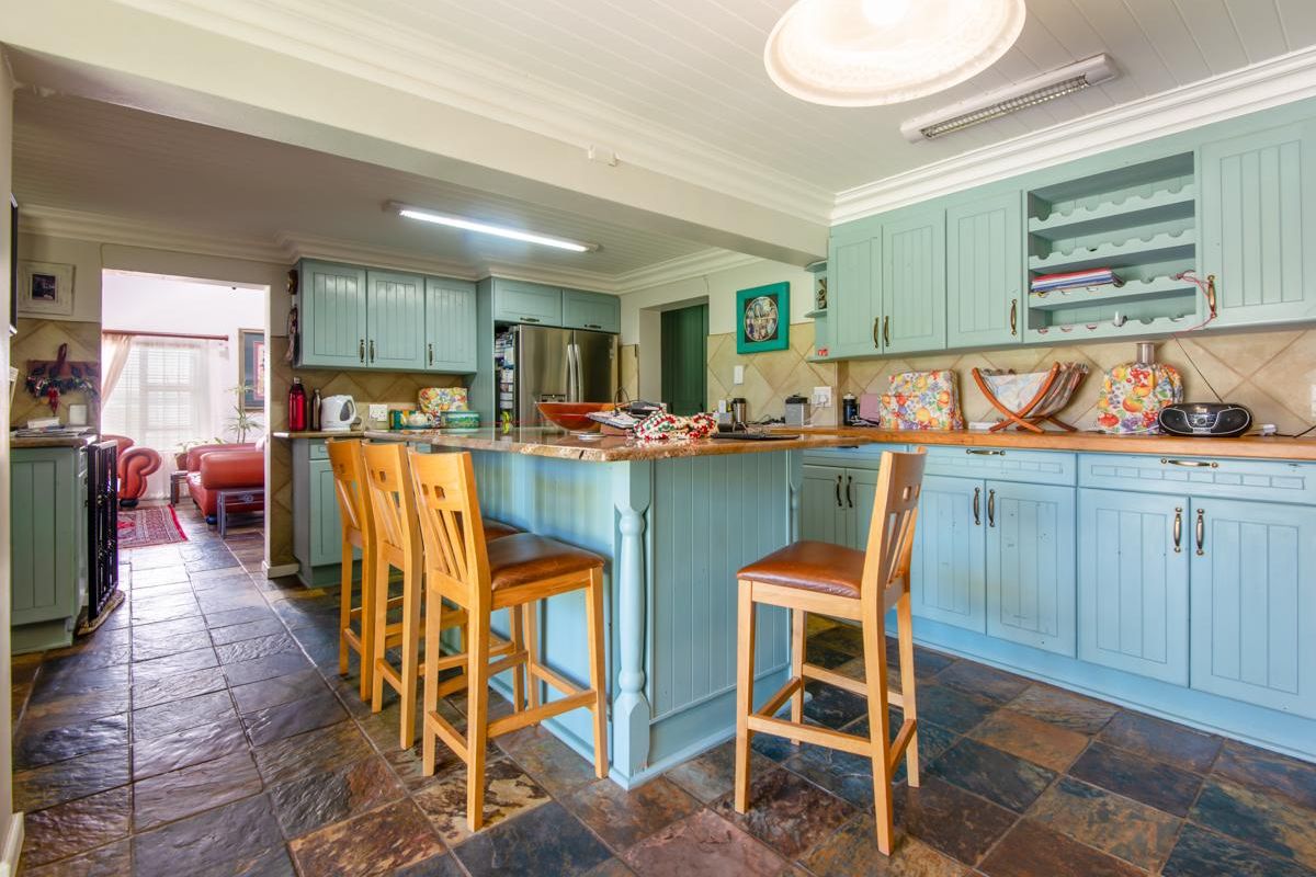Spacious kitchen featuring light blue cabinetry, a central island with breakfast bar seating, and durable slate-style floor tiles.
