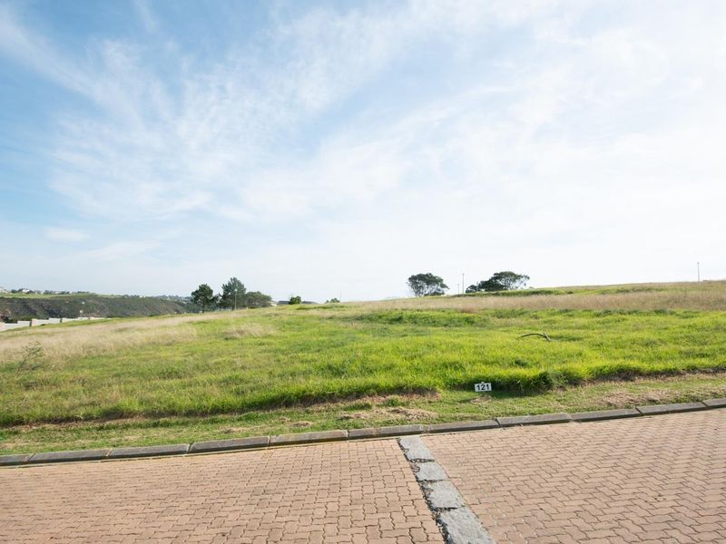 A vacant residential plot featuring a gentle slope, accessible from a paved street, offering an open landscape suitable for new construction.