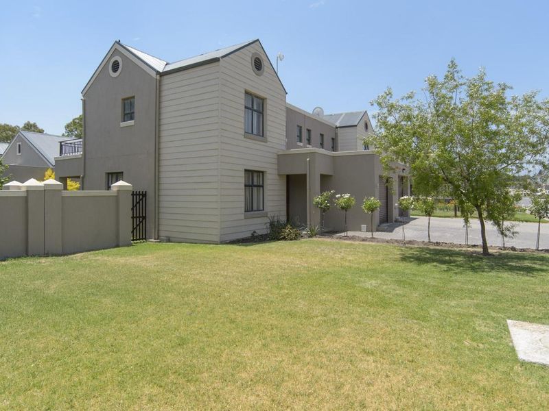 A well-maintained double-story residential property featuring a paved driveway, garage access, and a neat front garden with boundary walling.