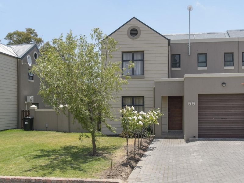 Front elevation of a two-story residential property featuring a paved driveway, single garage, and well-maintained garden area.