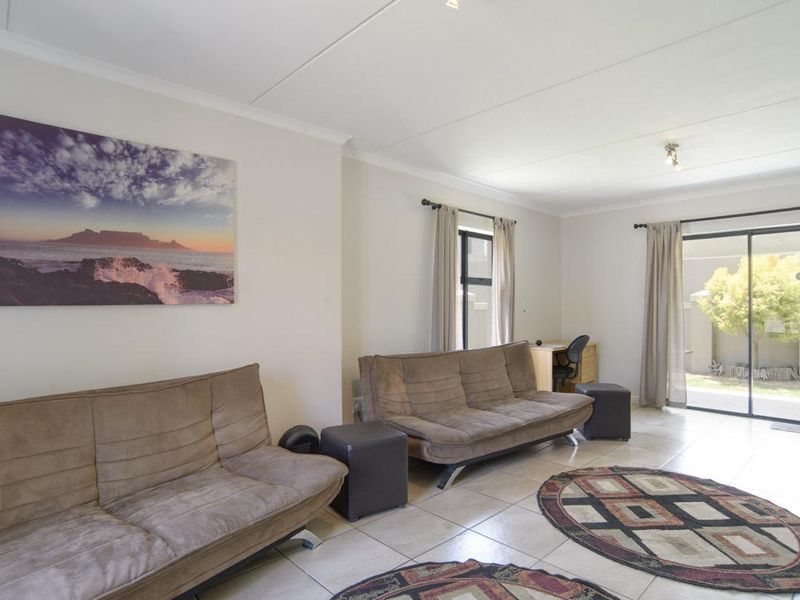 A bright living room featuring tiled flooring and a large sliding glass door providing access to the outdoor area.