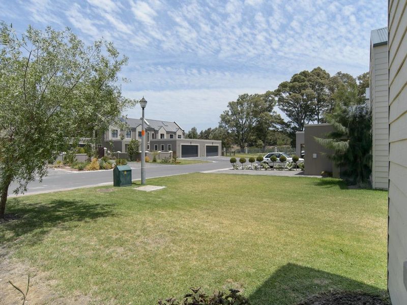 A view of the residential street and surrounding neighborhood landscape, featuring paved access and well-maintained communal green spaces.
