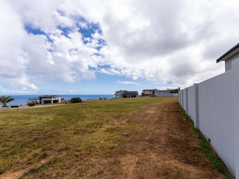 A vacant residential plot featuring a boundary wall and expansive views of the surrounding neighborhood and ocean.