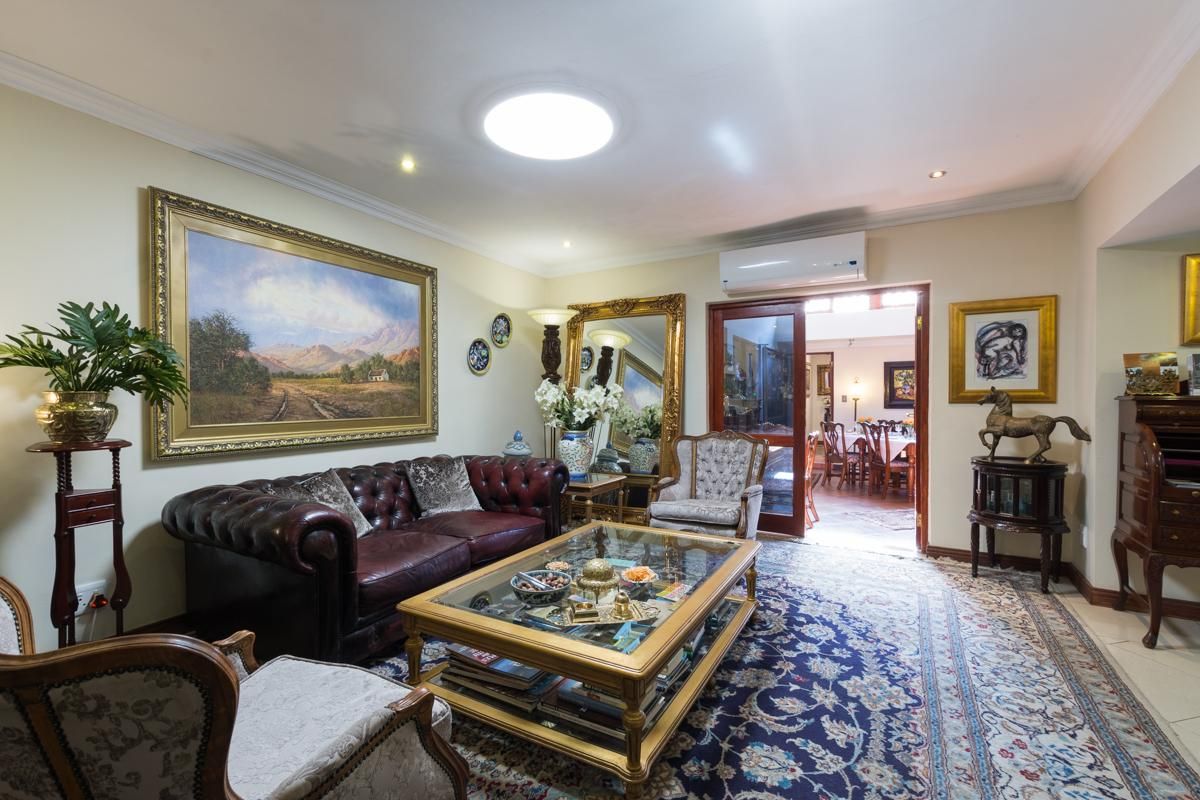 A well-maintained living room featuring recessed lighting, a wall-mounted air conditioning unit, and double doors leading to an adjacent dining area.
