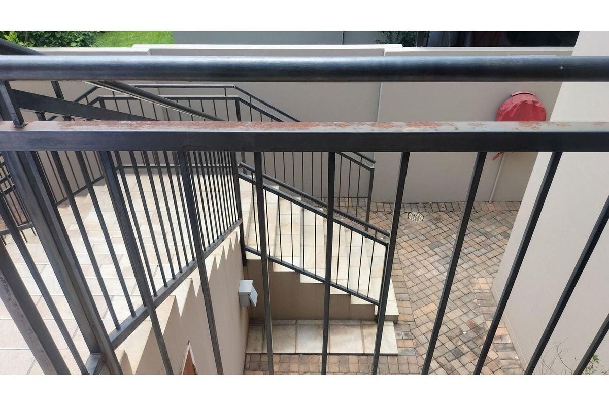 Exterior staircase with metal railings leading down to a paved courtyard area.