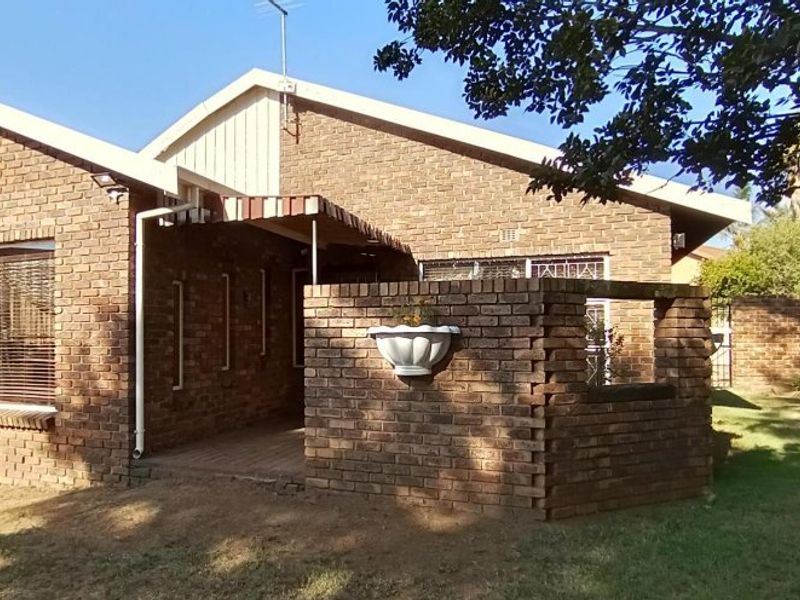 A view of the exterior front facade featuring face-brick construction, a covered entrance area, and a small brick privacy wall.