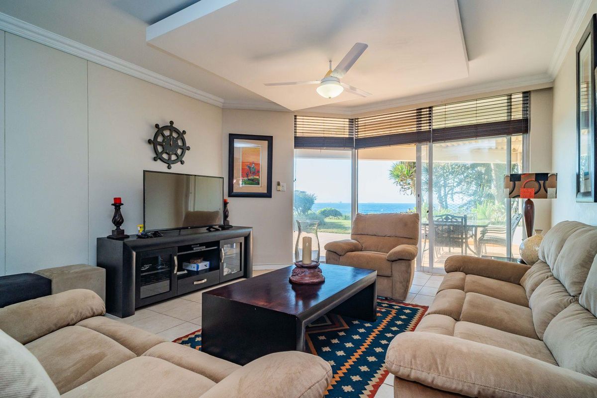 A comfortable living room featuring a recessed ceiling with a fan, tiled floors, and large sliding glass doors that open to an outdoor patio area.