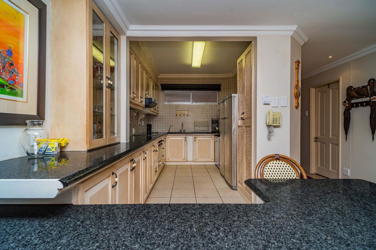 A functional kitchen featuring granite countertops, ample built-in cabinetry, tiled backsplash, and ceramic flooring, offering a classic layout with integrated storage solutions.