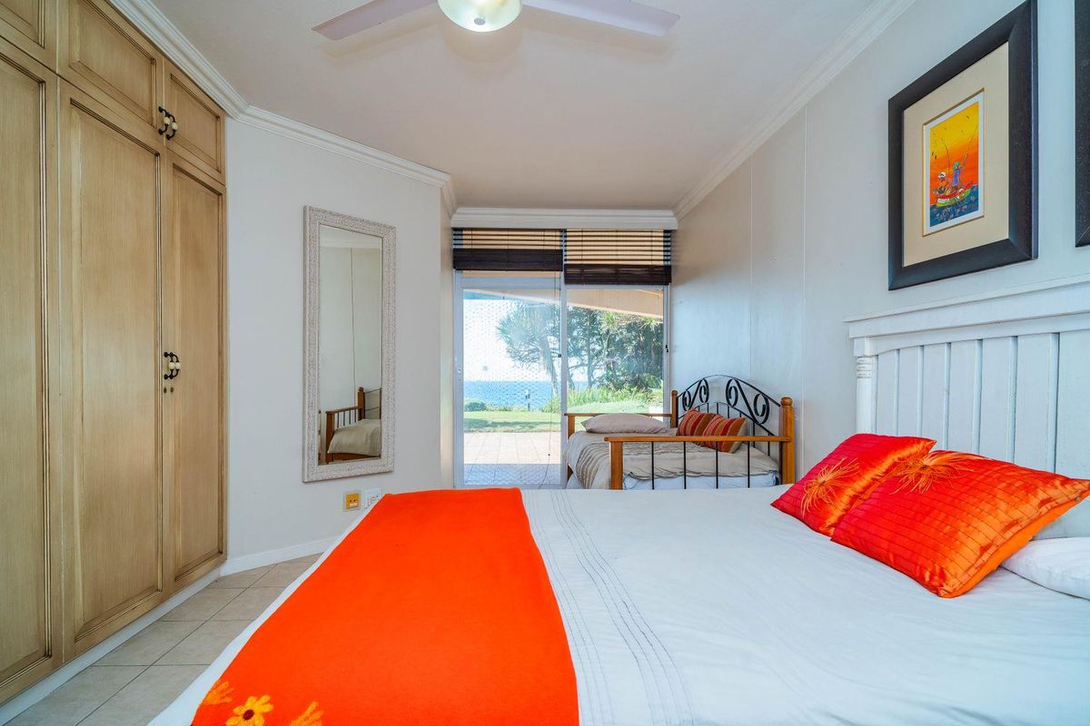 A bedroom featuring built-in wooden cupboards, tiled flooring, and a sliding glass door providing direct access to an outdoor patio area.