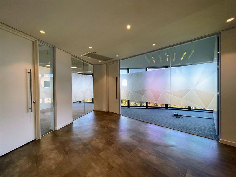 Modern office space featuring glass partition walls, recessed lighting, and high-quality vinyl flooring, offering a bright and professional work environment.