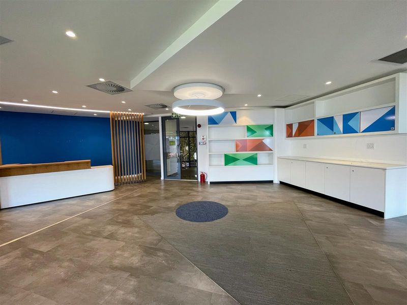 A modern, well-maintained office reception area featuring built-in cabinetry, a reception desk, and contemporary recessed lighting.