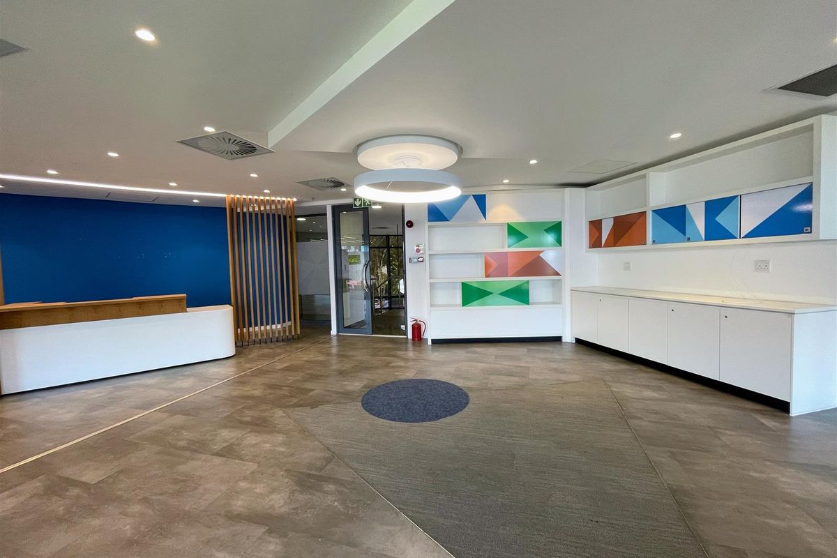 A modern, well-maintained office reception area featuring built-in cabinetry, a reception desk, and contemporary recessed lighting.