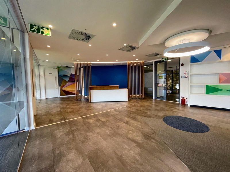 Modern office reception area featuring a built-in desk, glass partitioning, recessed lighting, and clean, contemporary finishes throughout the entrance space.