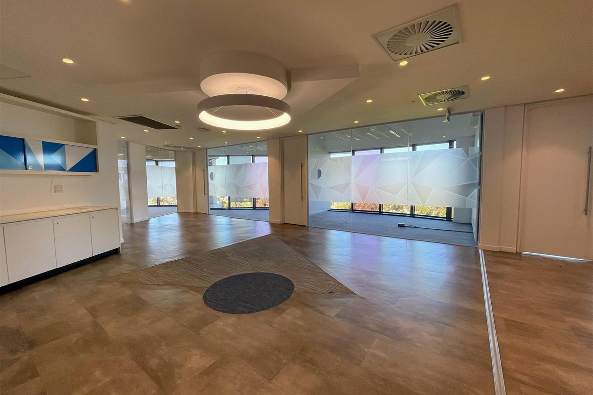 Modern open-plan office space featuring glass partitions, built-in cabinetry, recessed lighting, and large windows with frosted privacy film.