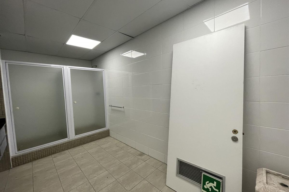 A functional bathroom space featuring tiled walls and flooring, a shower enclosure, and recessed lighting, currently requiring maintenance and repair.