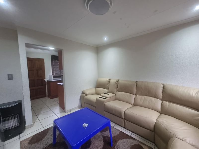 A living room area featuring tiled flooring and recessed lighting, with visible ceiling water staining requiring attention.