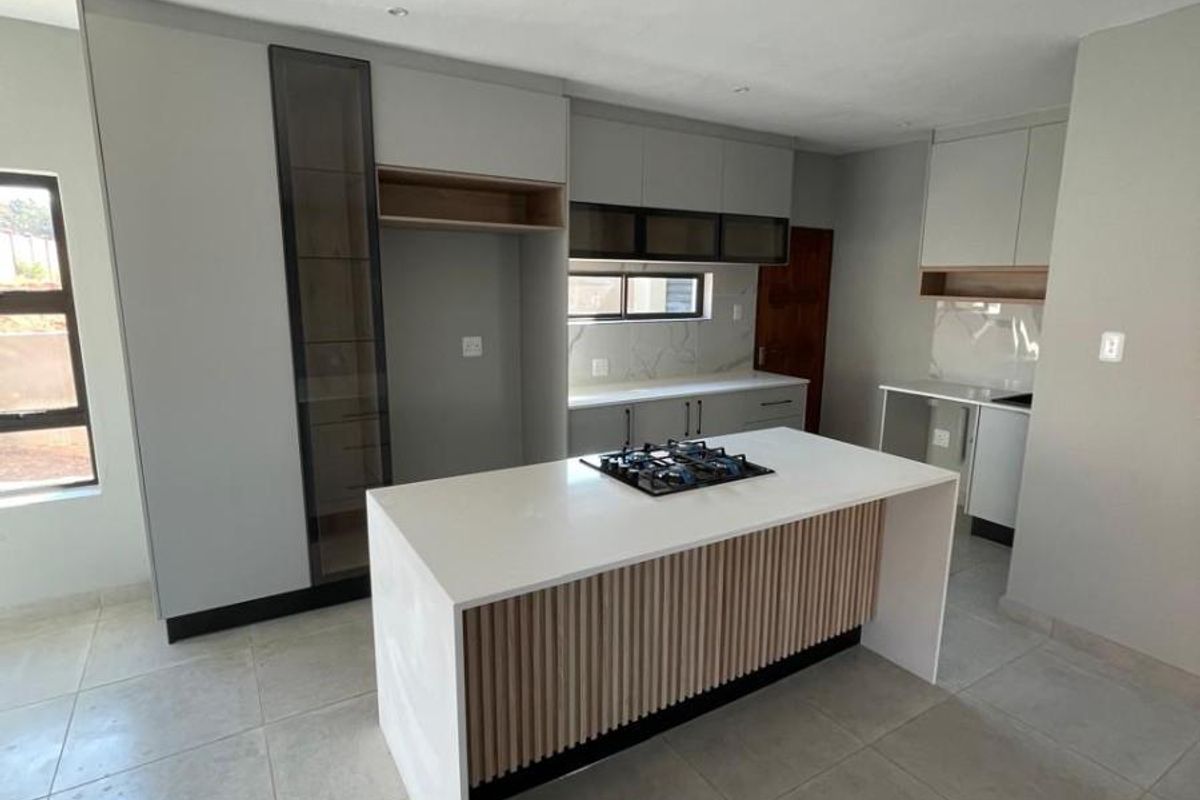 Modern kitchen featuring a central island with a built-in gas hob, sleek cabinetry, quartz countertops, and contemporary slatted wood detailing.