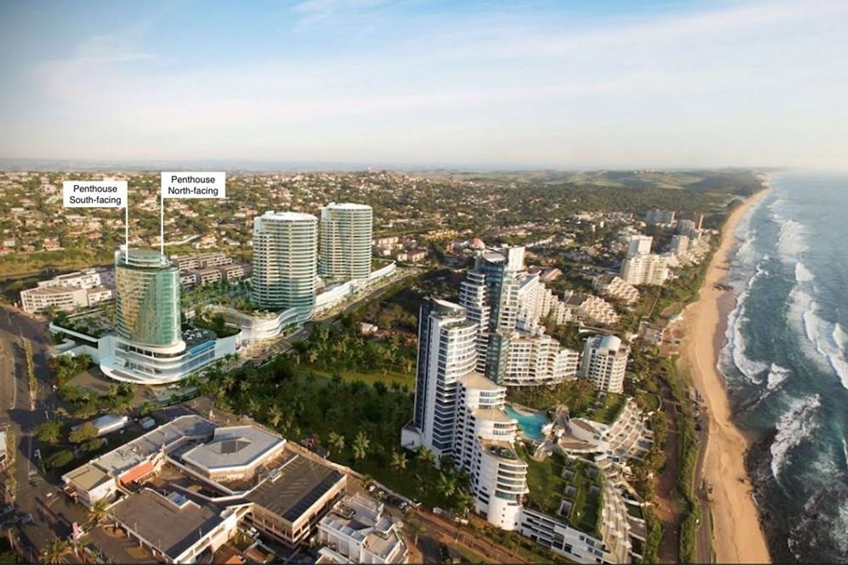 Aerial view of the coastal development featuring modern high-rise penthouse towers situated near the beach and surrounding urban infrastructure.