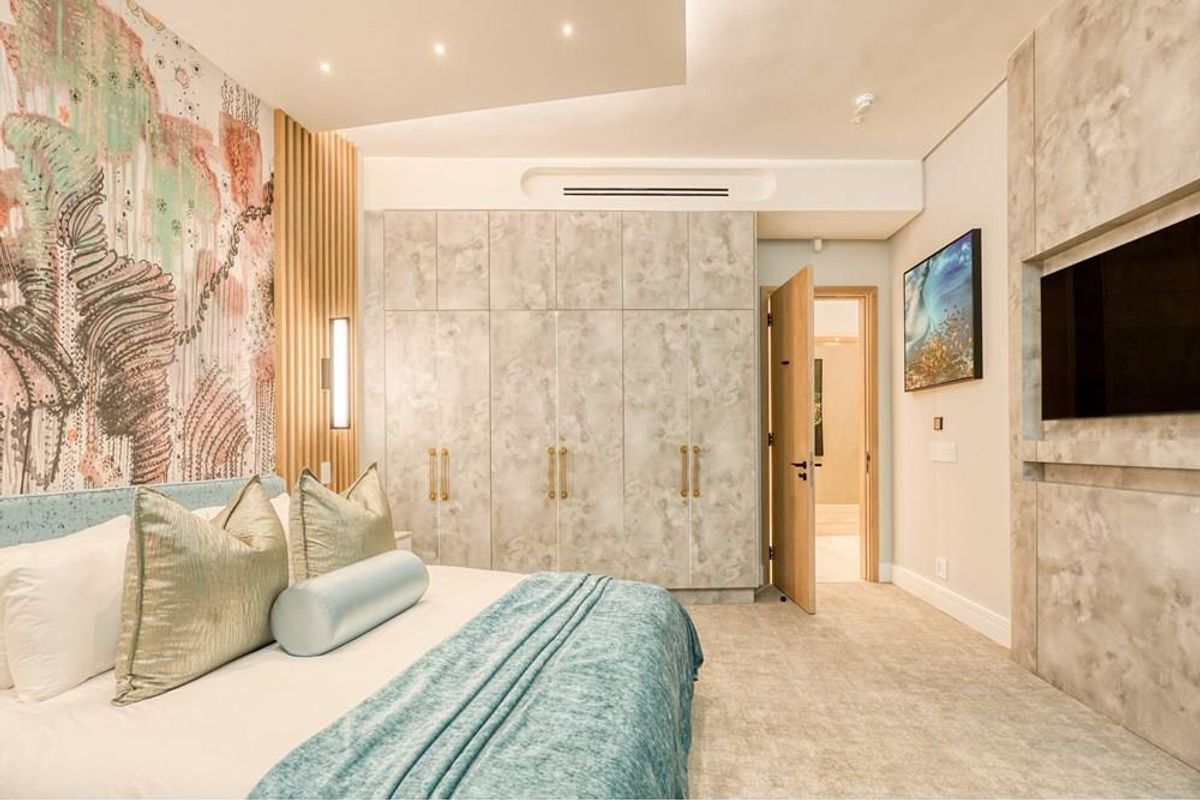 Modern luxury bedroom featuring custom built-in wardrobes, integrated media wall, recessed ceiling lighting, and sophisticated wall paneling finishes.