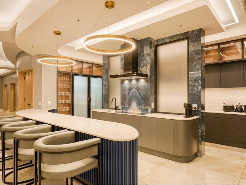 Modern luxury kitchen featuring a curved stone breakfast bar, premium cabinetry, integrated appliances, and sophisticated pendant lighting in a high-end penthouse setting.