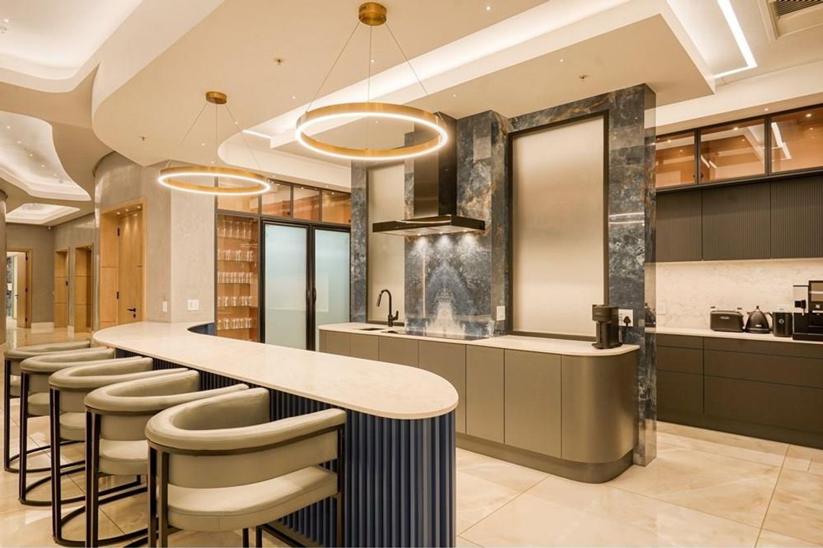 Modern luxury kitchen featuring a curved stone breakfast bar, premium cabinetry, integrated appliances, and sophisticated pendant lighting in a high-end penthouse setting.
