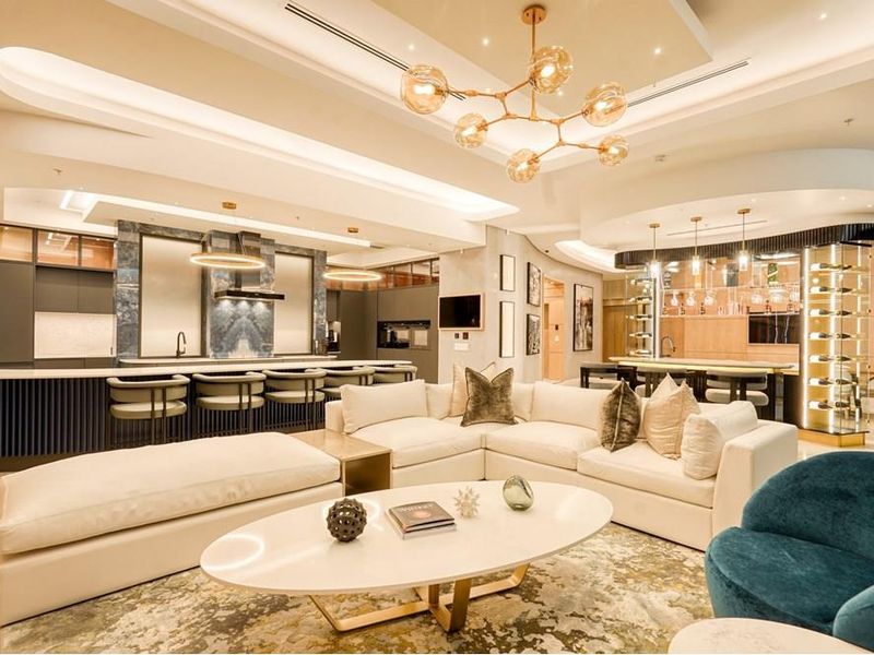 Luxurious open-plan living area featuring a modern kitchen with stone finishes, integrated wine display, and sophisticated recessed ceiling lighting throughout the space.