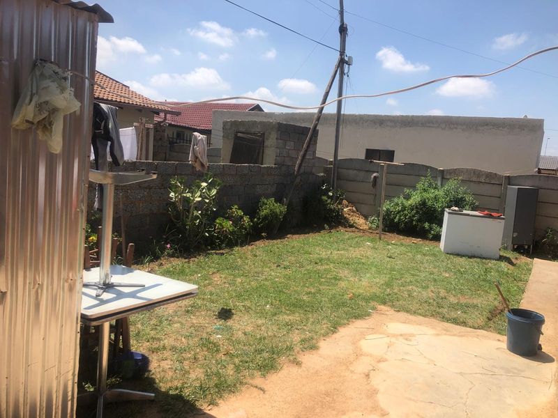 A rear garden area featuring a lawn, paved section, and concrete block boundary walls, requiring landscaping and maintenance to improve the outdoor space.