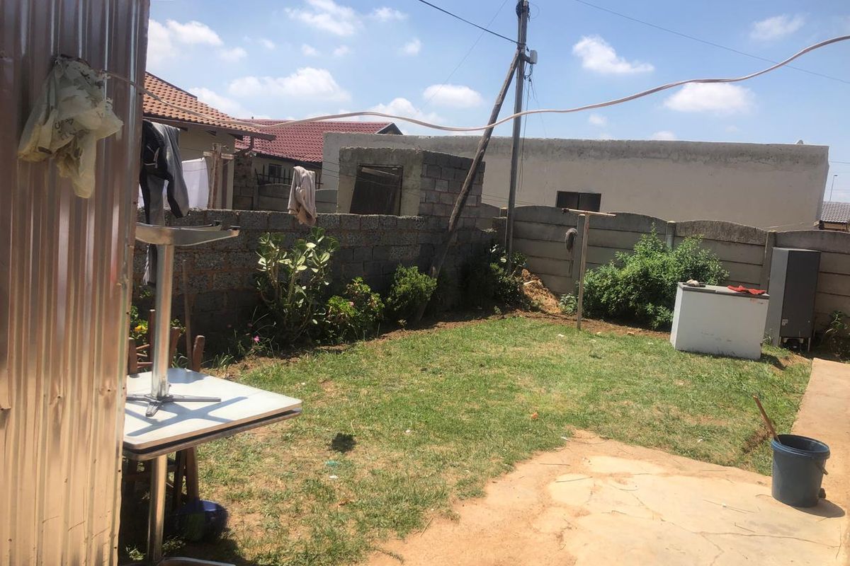 A rear garden area featuring a lawn, paved section, and concrete block boundary walls, requiring landscaping and maintenance to improve the outdoor space.