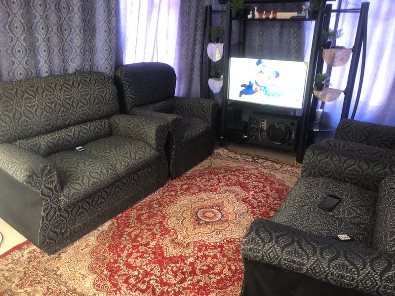 A living room space featuring patterned curtains and a central area rug.