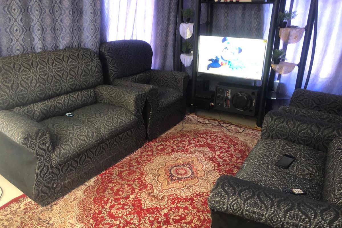 A living room space featuring patterned curtains and a central area rug.