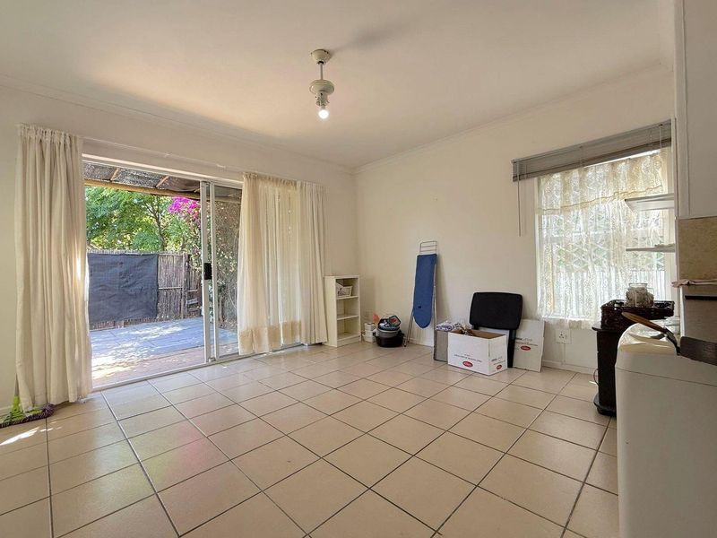 A bright, tiled living area featuring a large sliding glass door that provides direct access to the outdoor patio space.
