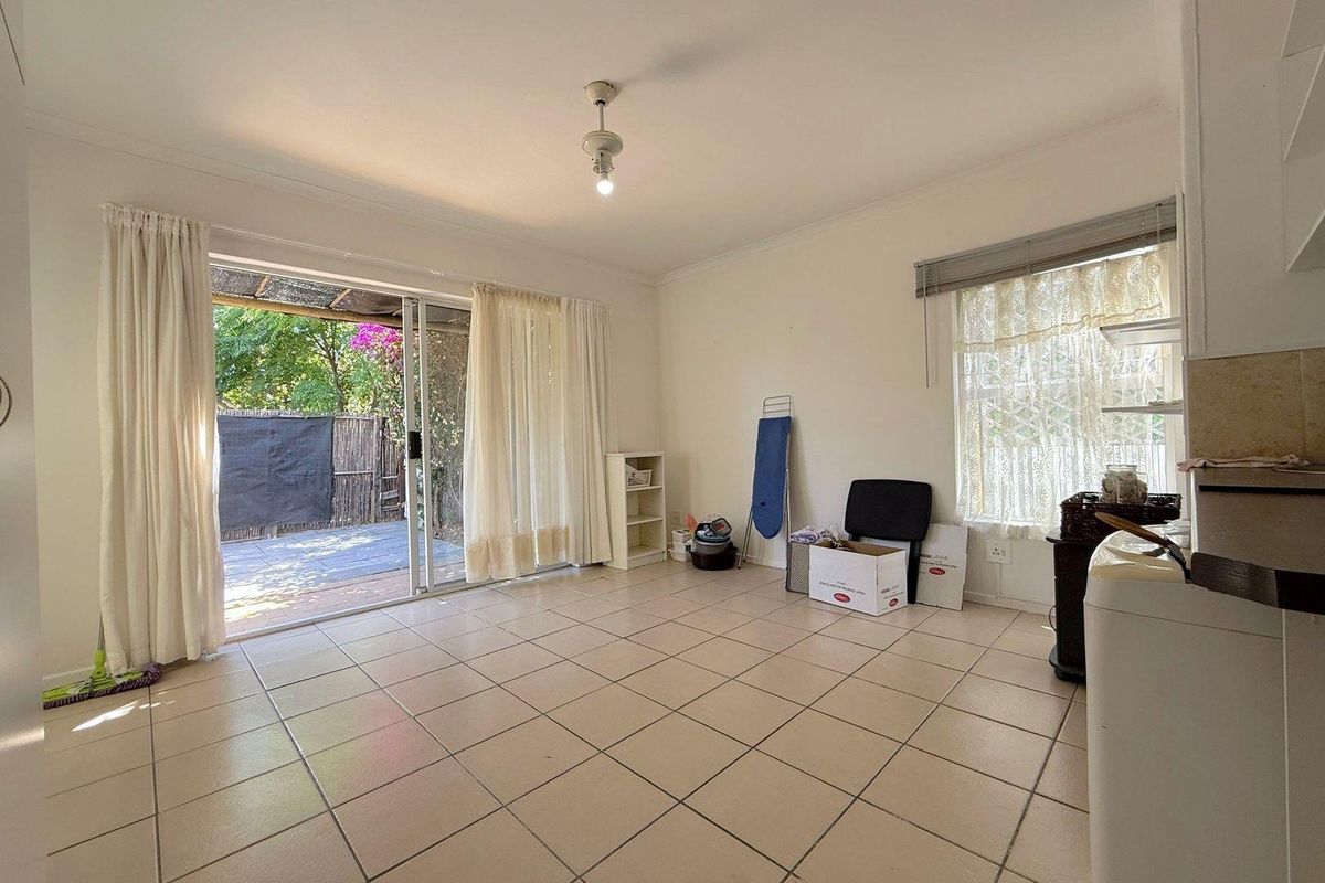 A bright, tiled living area featuring a large sliding glass door that provides direct access to the outdoor patio space.