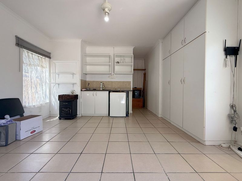 A compact, functional kitchen area featuring tiled flooring, built-in cabinetry, and a sink, offering a blank canvas for potential renovation or modernization.