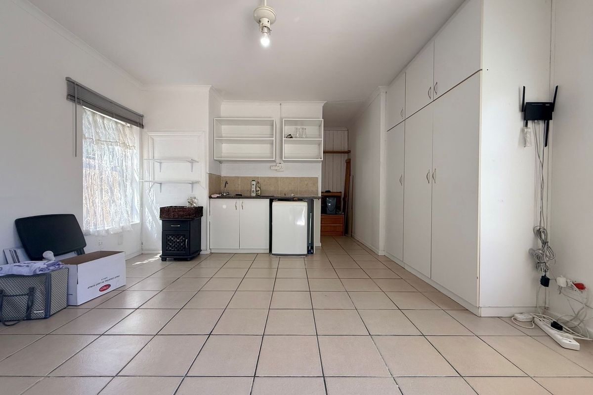 A compact, functional kitchen area featuring tiled flooring, built-in cabinetry, and a sink, offering a blank canvas for potential renovation or modernization.