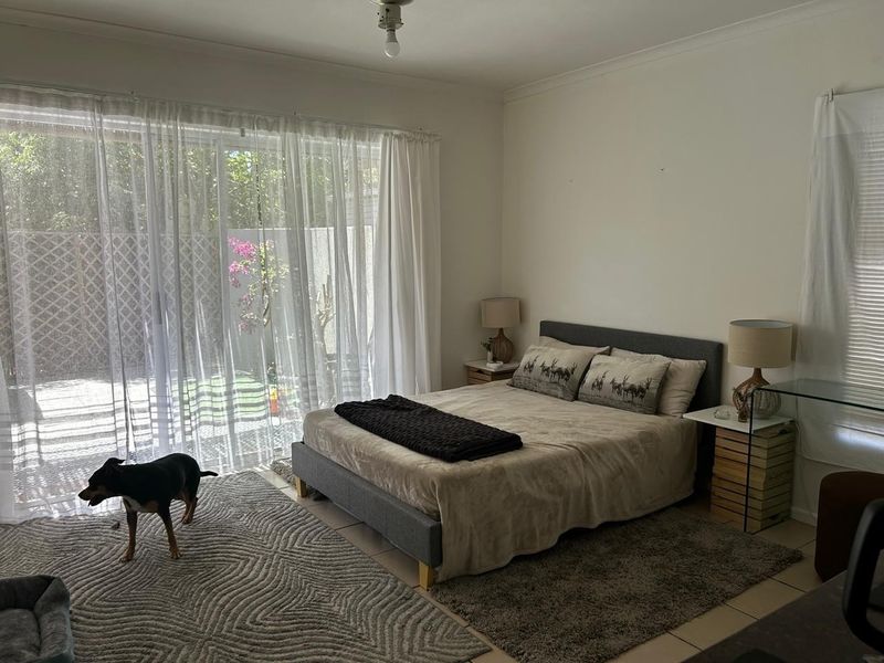 A bedroom featuring tiled flooring and a large sliding glass door providing direct access to the outdoor area.