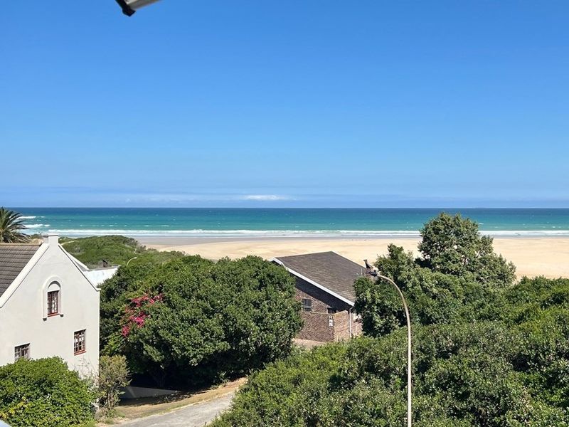 A scenic elevated view overlooking the coastline, sandy beach, and ocean, capturing the natural beauty of the surrounding landscape.