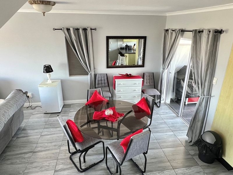 A bright open-plan dining area featuring tiled flooring, sliding glass doors leading to an outdoor space, and neutral wall finishes.