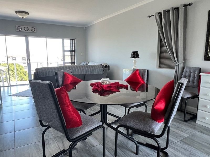 Open plan living and dining area featuring tiled flooring, large sliding glass doors leading to a balcony, and neutral wall finishes.