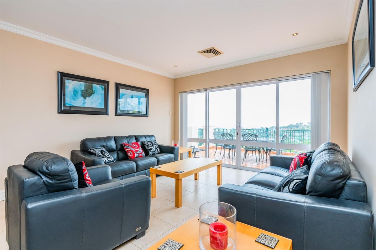 Spacious living room featuring large sliding glass doors that open onto a private balcony, providing ample natural light and outdoor access.