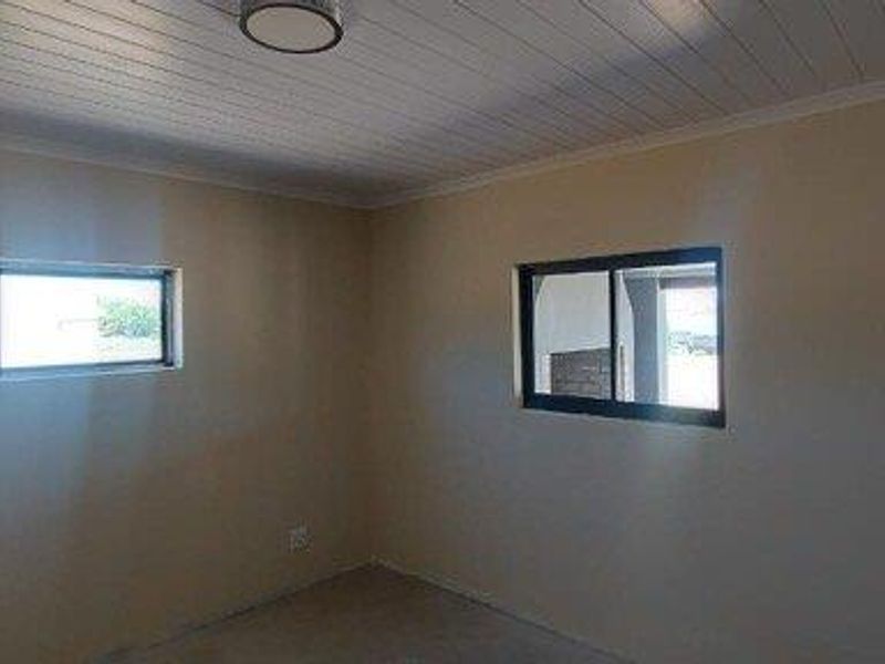 A vacant bedroom featuring neutral walls, a tongue-and-groove ceiling, and sliding windows, offering a blank canvas for personalization.