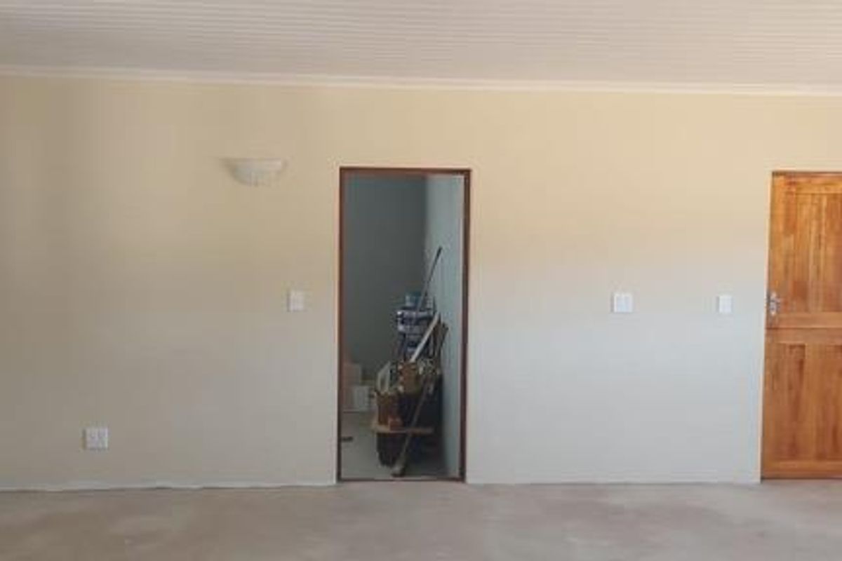 An interior view of a room featuring a wooden door, wall-mounted light fixtures, and an open doorway leading to an adjacent space.